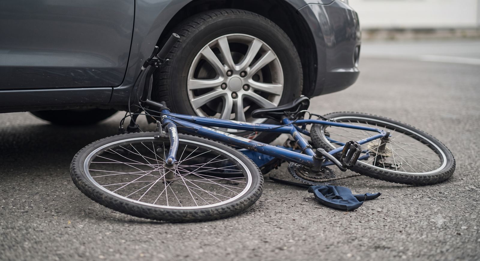 A bicycle knocked over next to a car's rear wheel after a collision